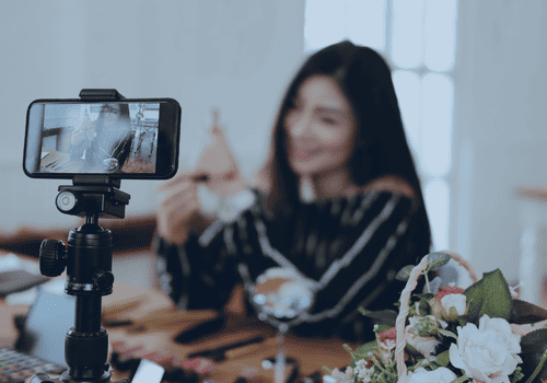 influencer in background using her mobile phone to record content in the foreground