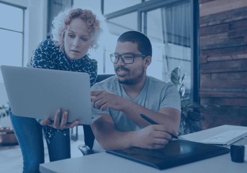 two people on a laptop in an office discussing PPC Ads